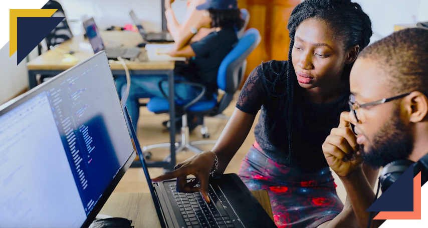 Girl pointing to laptop screen to help fellow student with their coding